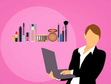 graphic of a pink background with a faceless woman wearing a suit holding a grey laptop with an assortment of makeup products displayed behind her