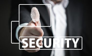 man in black suit putting his thumb on the screen with ink showing his print with word security written underneath
