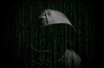 shadow of a grey hoodie with green computer coding running down over top to signify a hacker hacking