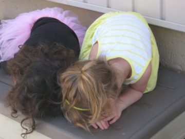 two little girls hunched over counting one wearing a pink tutu and the other wearing a yellow dress