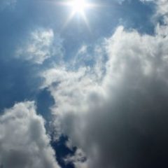 pale blue sky with scattered clouds sun shinging through