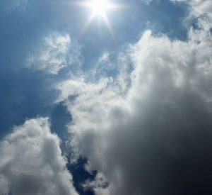 pale blue sky with scattered clouds sun shinging through