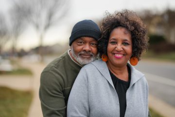 middle age african american couple smiling while embracing on the street