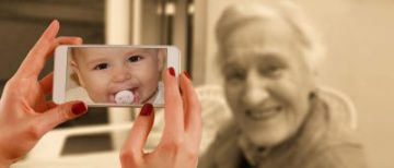 young hands holding a phone camera up to an elderly woman shows a baby face peering back instead