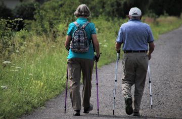 elderly couple walking into the distance using walking sticks for endurance